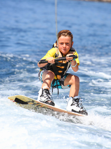 A young boy on a wake-board being towed by a boat.