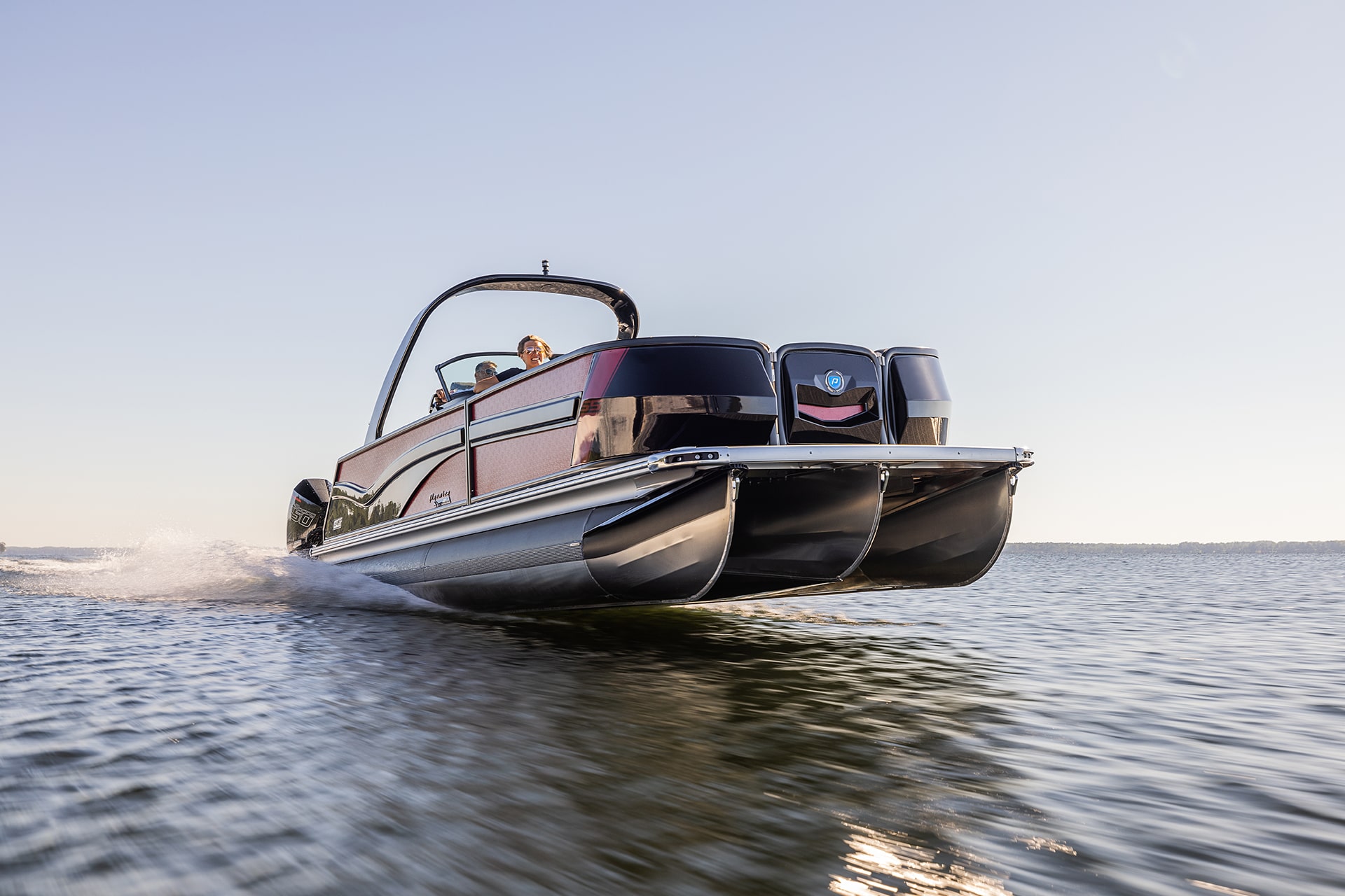 Head-on shot of a performance tritoon racing down a lake.