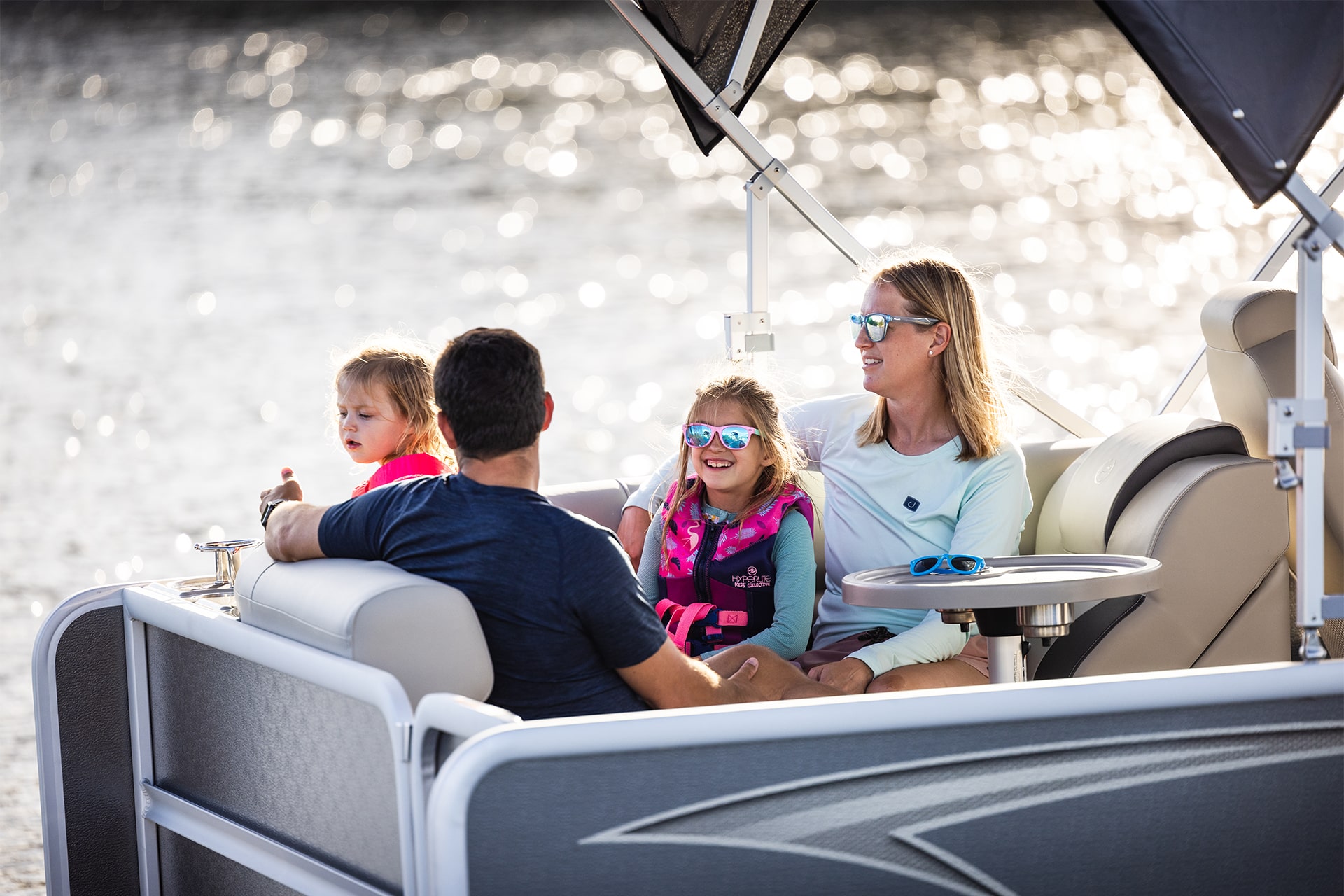 A mother, father and two girls are relaxing on the back of a Premier pontoon.