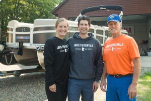 Michelle, Lane, and Ken Mimmack standing in front of a tritoon boat
